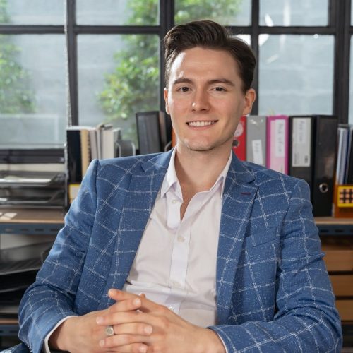 close-up-portrait-young-businessman-smiling-to-camera-in-office-e1658719612851.jpg